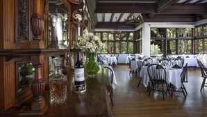 A dining area with wooden paneling, a bar with bottles and glasses, and tables set for dining.