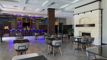 A modern bar area with a stone fireplace, seating arrangements, and a bar counter.