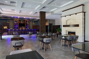 A modern restaurant with a stone fireplace, bar area, and seating arrangements. - Four Points by Sheraton Houston West (Houston)