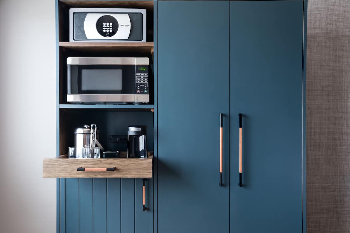 Une cuisine équipée d’un four à micro-ondes, d’un four et d’une machine à café, le tout placé sur une étagère en bois.