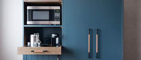 A kitchen with a microwave, oven, and coffee maker on a wooden shelf.