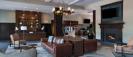 Een hotel lobby met een open haard, zithoek en een bar.