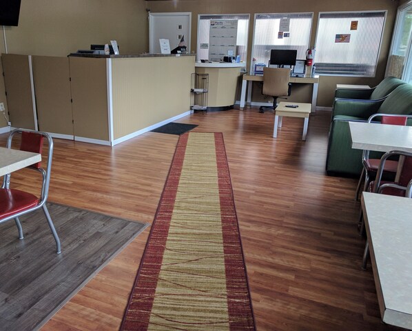 A reception area with a desk, chairs, a small table, and a couch. - Simplicity Inn (Marshfield)