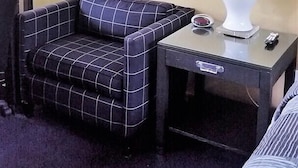 Ett hotellrum med en soffa, ett litet bord med en lampa och en spegel som hänger på väggen.