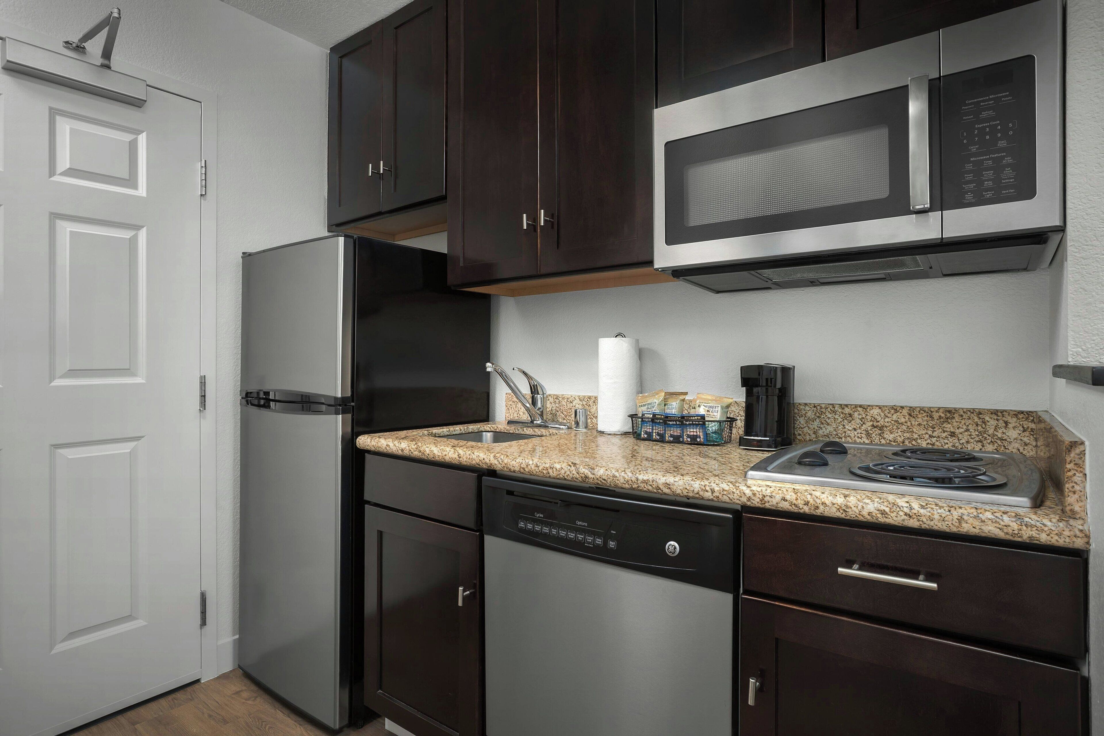 A compact kitchen with a refrigerator, dishwasher, microwave, and stove.