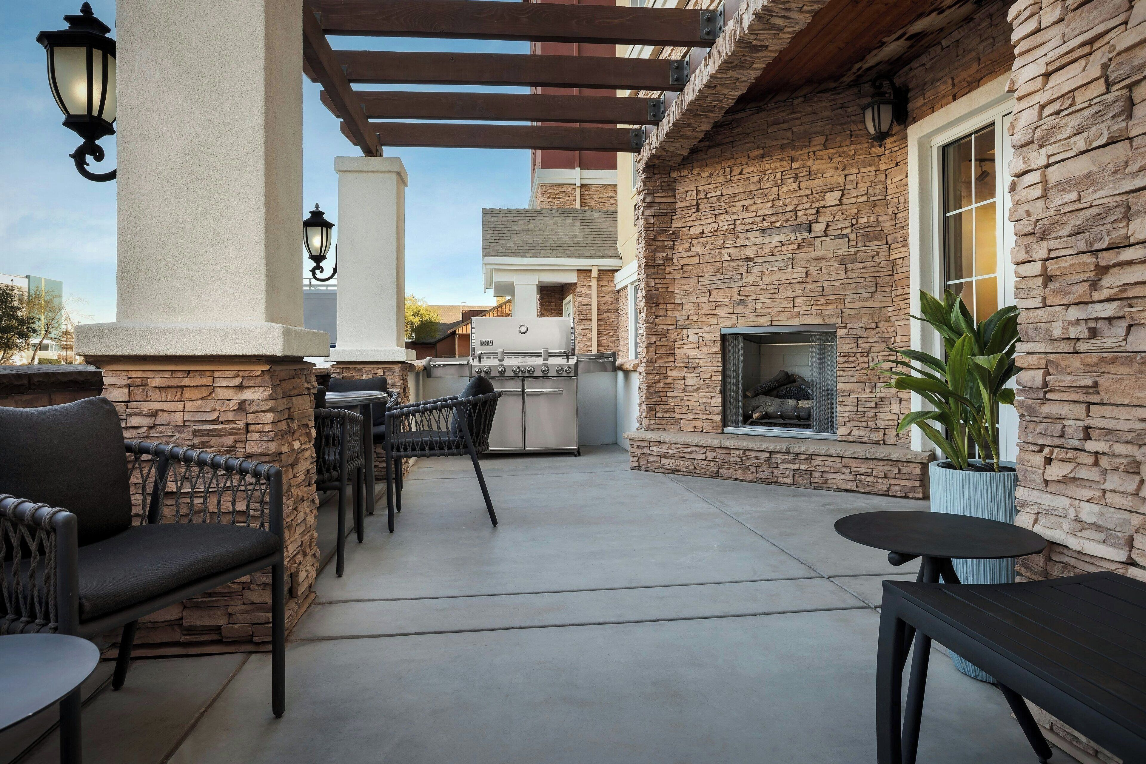 An outdoor patio area with stone walls, a grill, and seating.