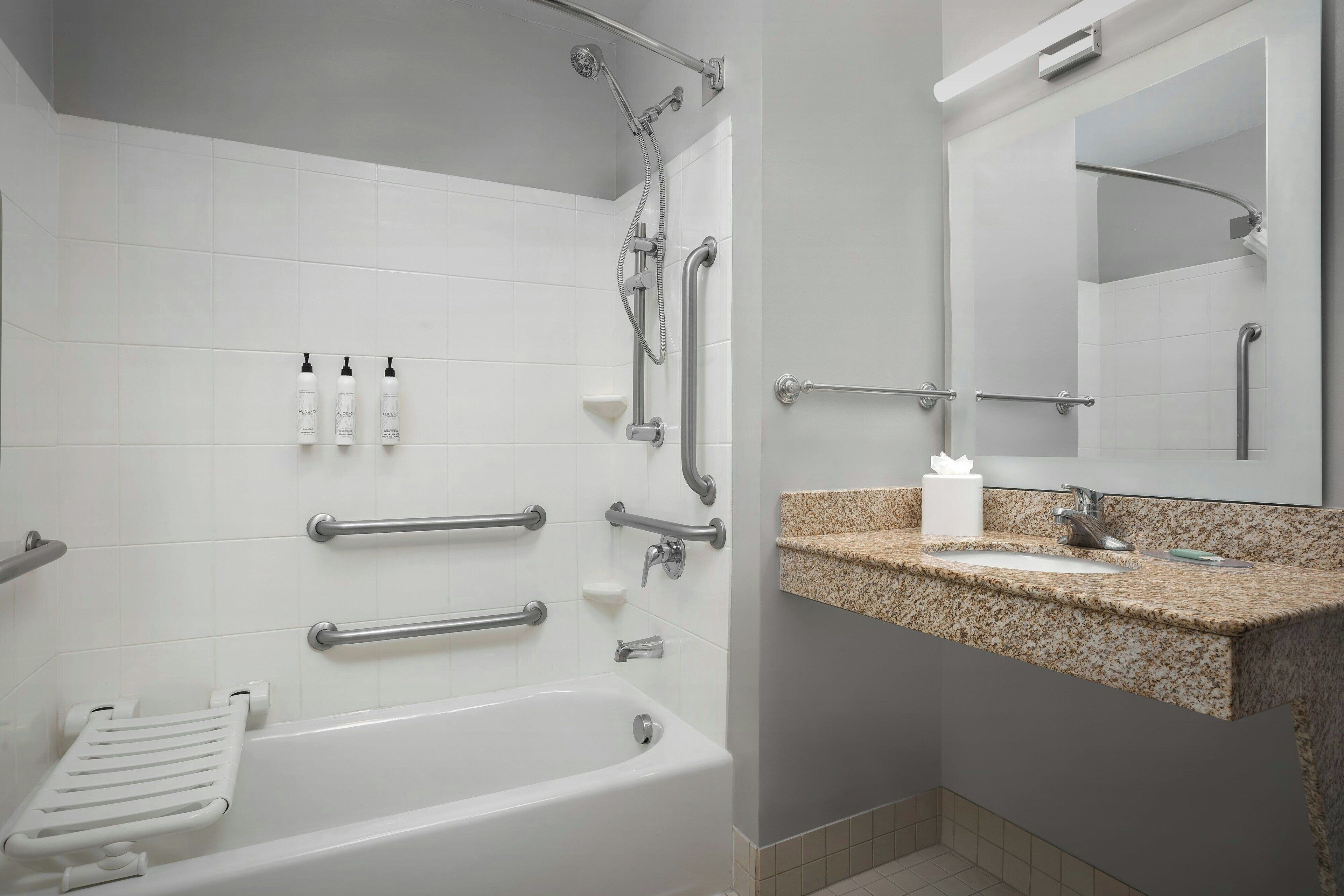 Un baño moderno con bañera, ducha y tocador con lavabo y espejo.