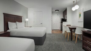 A hotel room with two beds, a desk, chairs, a television, and a kitchenette. - TownePlace Suites Marriott El Centro (El Centro)
