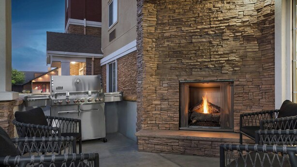 An outdoor patio with stone walls, a fireplace, and outdoor kitchen equipment. - TownePlace Suites Marriott El Centro (El Centro)