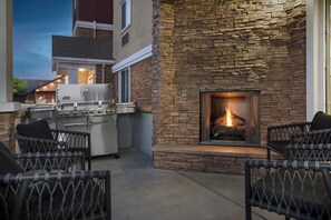 Un patio al aire libre con paredes de piedra, chimenea y equipamiento de cocina exterior.