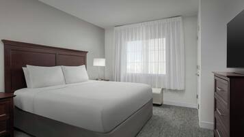 A hotel room with a large bed, a nightstand, a lamp, a dresser, and a television.