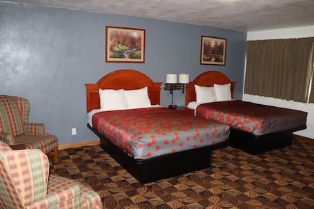 A hotel room with two beds, a chair, and two paintings on the wall.