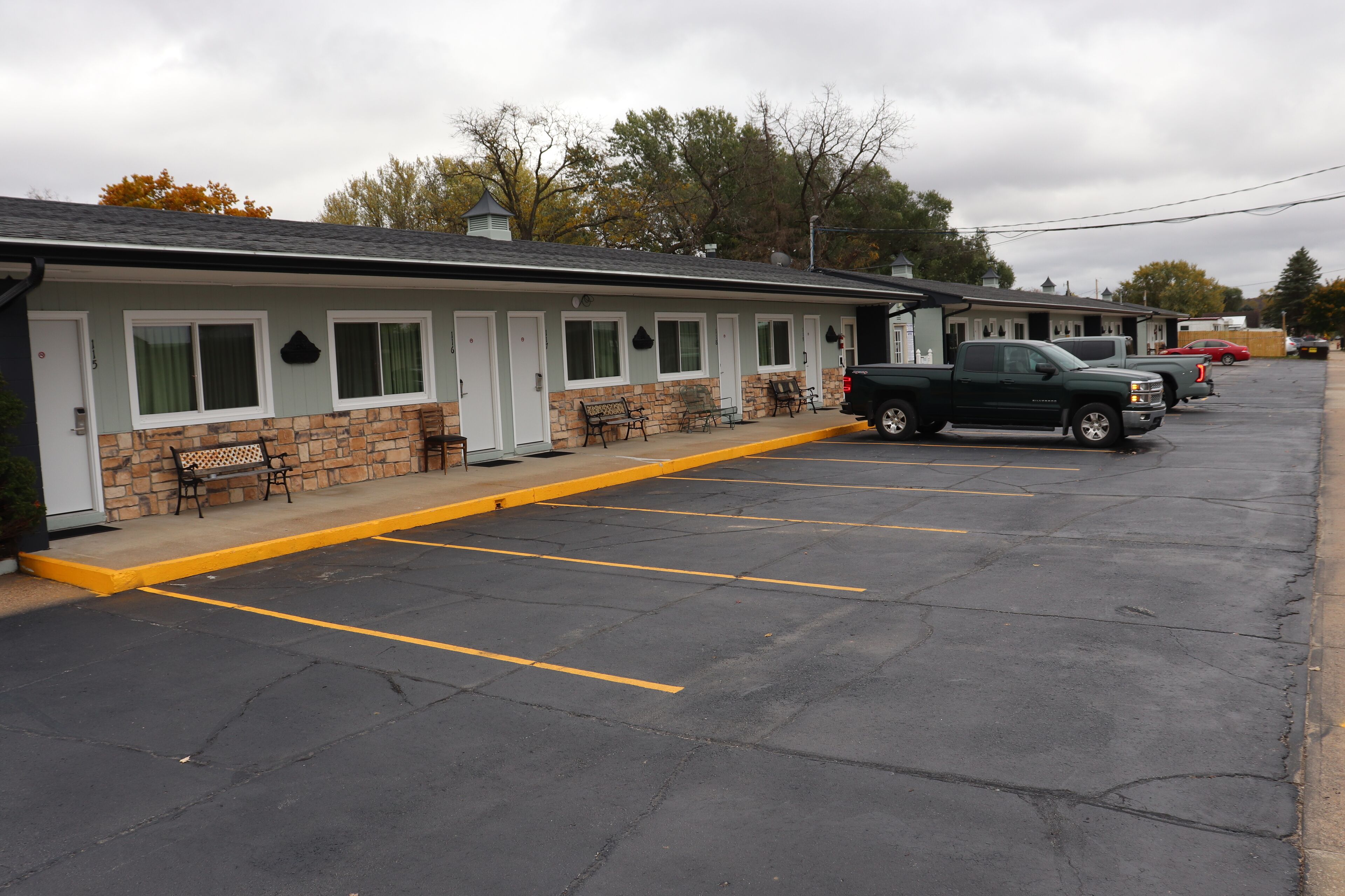 A motel with a row of rooms, a parking lot, and a green pickup truck parked in front.