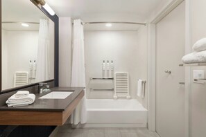 Une salle de bain moderne avec un meuble-lavabo à deux vasques, une baignoire, une douche avec rideau et un grand miroir.