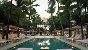 A poolside area with lounge chairs and umbrellas, surrounded by palm trees. - Grand Beach Hotel (Miami Beach)
