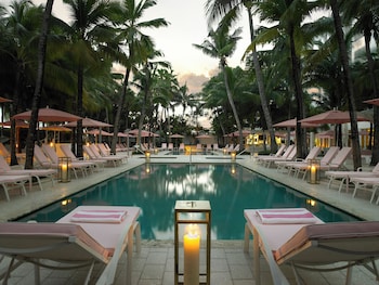 A beach walkway lined with palm trees and a hammock. at Grand Beach Hotel