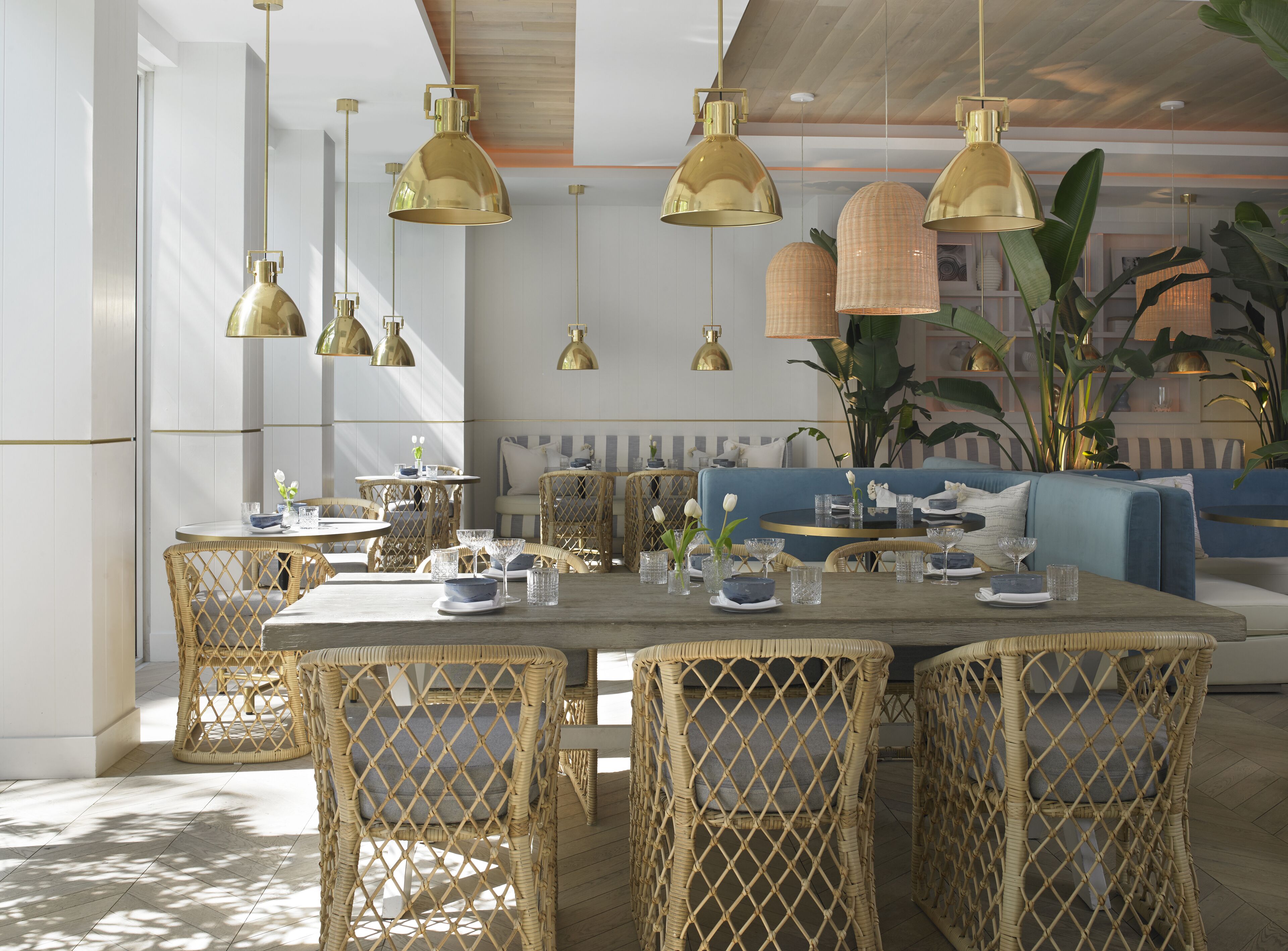 A dining area with wicker chairs, a wooden table, and gold pendant lights.