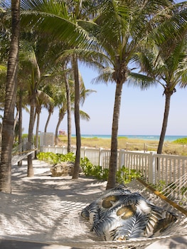 A modern lobby with a seating area, large windows, and hanging wicker lamps. at Grand Beach Hotel