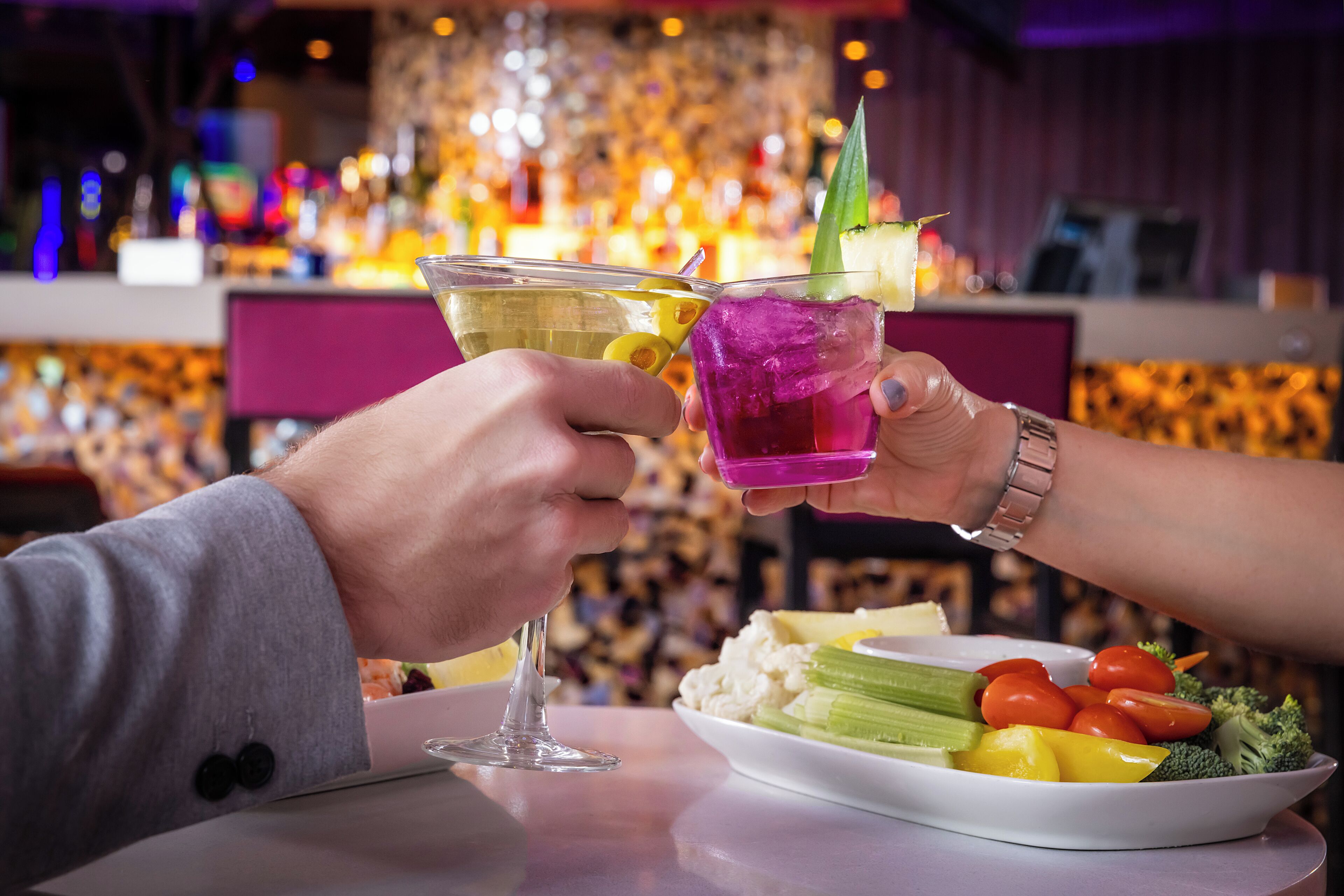 Un bar con una persona sosteniendo una copa de cóctel y una copa de martini.