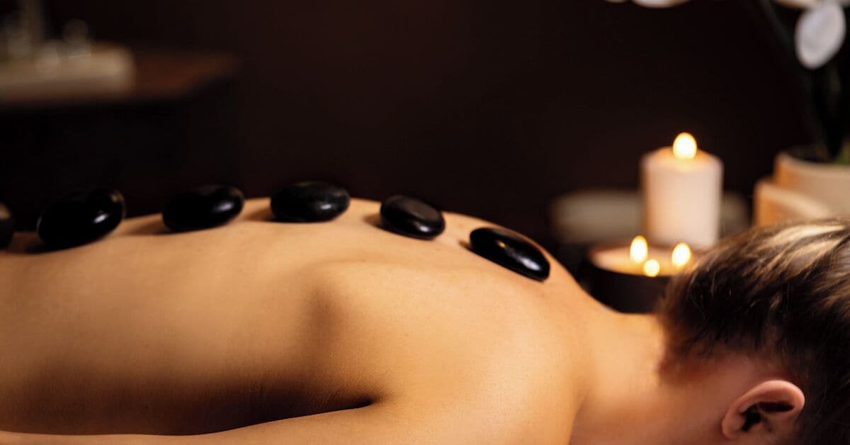 A person receiving a back massage with stones.