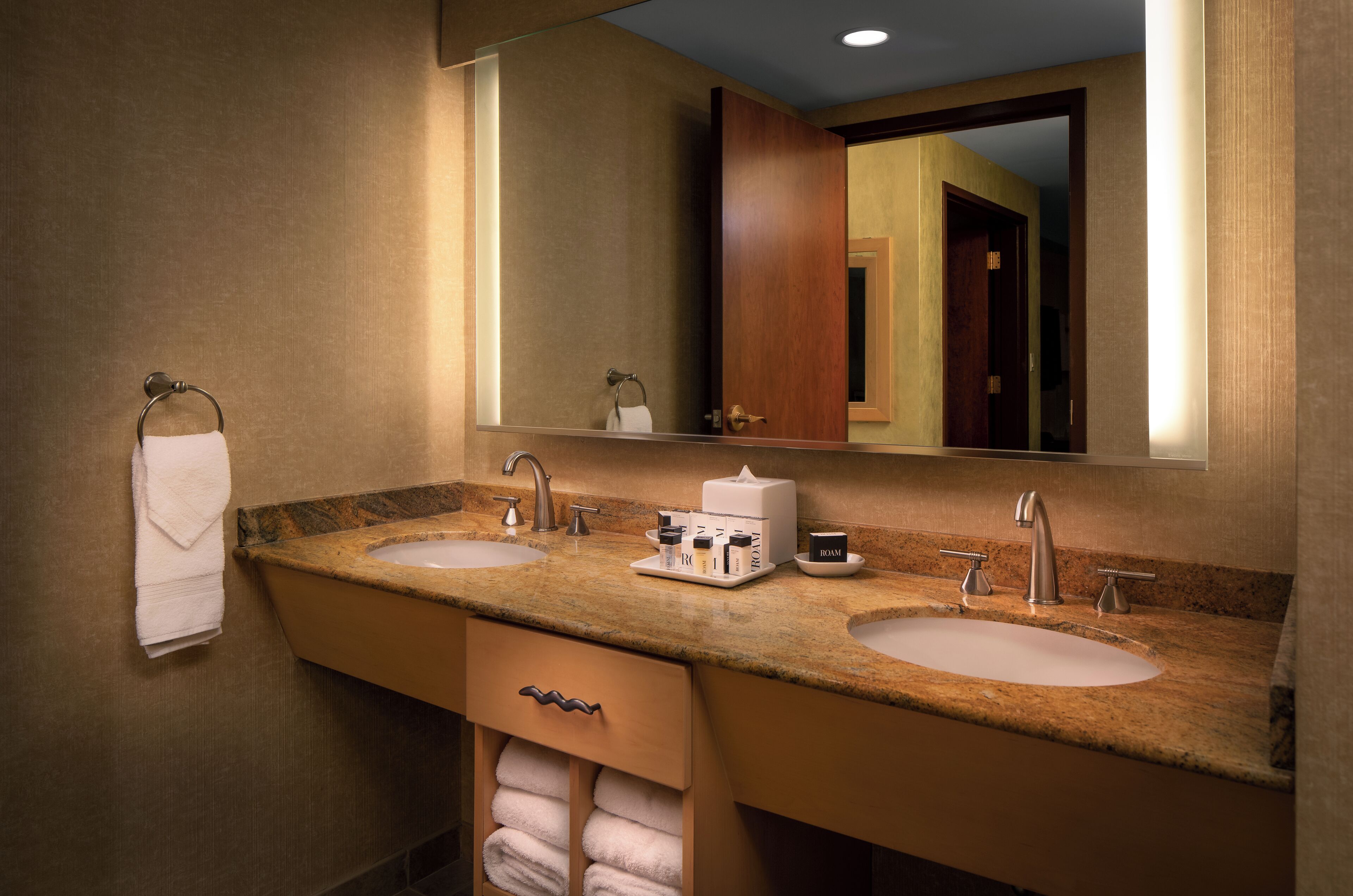 A bathroom with two sinks, a mirror, and a towel rack.
