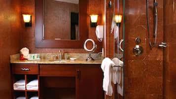 A bathroom with a vanity, mirror, towel rack, and a glass-enclosed shower area.