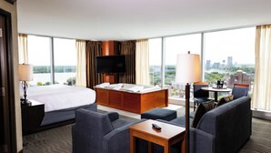 Hotelkamer met een groot bed, een bank, een televisie en uitzicht op een stadsbeeld.