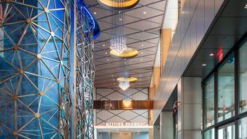 A modern building interior with a geometric wall structure, meeting rooms, and a blue carpet with directional arrows.