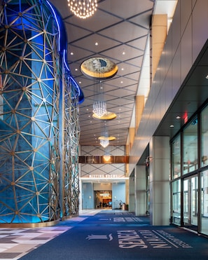 A modern building interior with a geometric wall structure, meeting rooms, and a blue carpet with directional arrows.