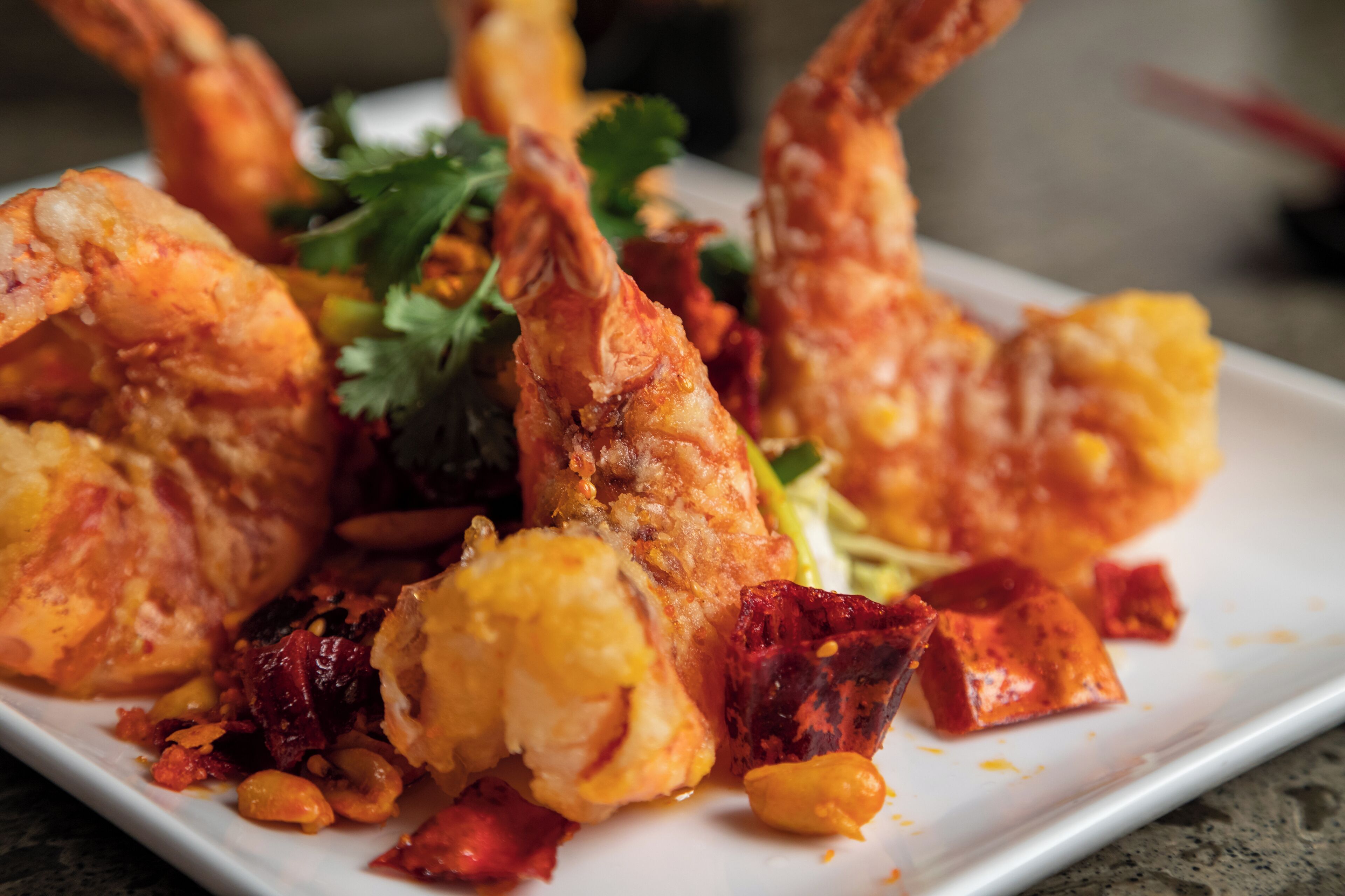 A plate of fried seafood with vegetables and herbs.