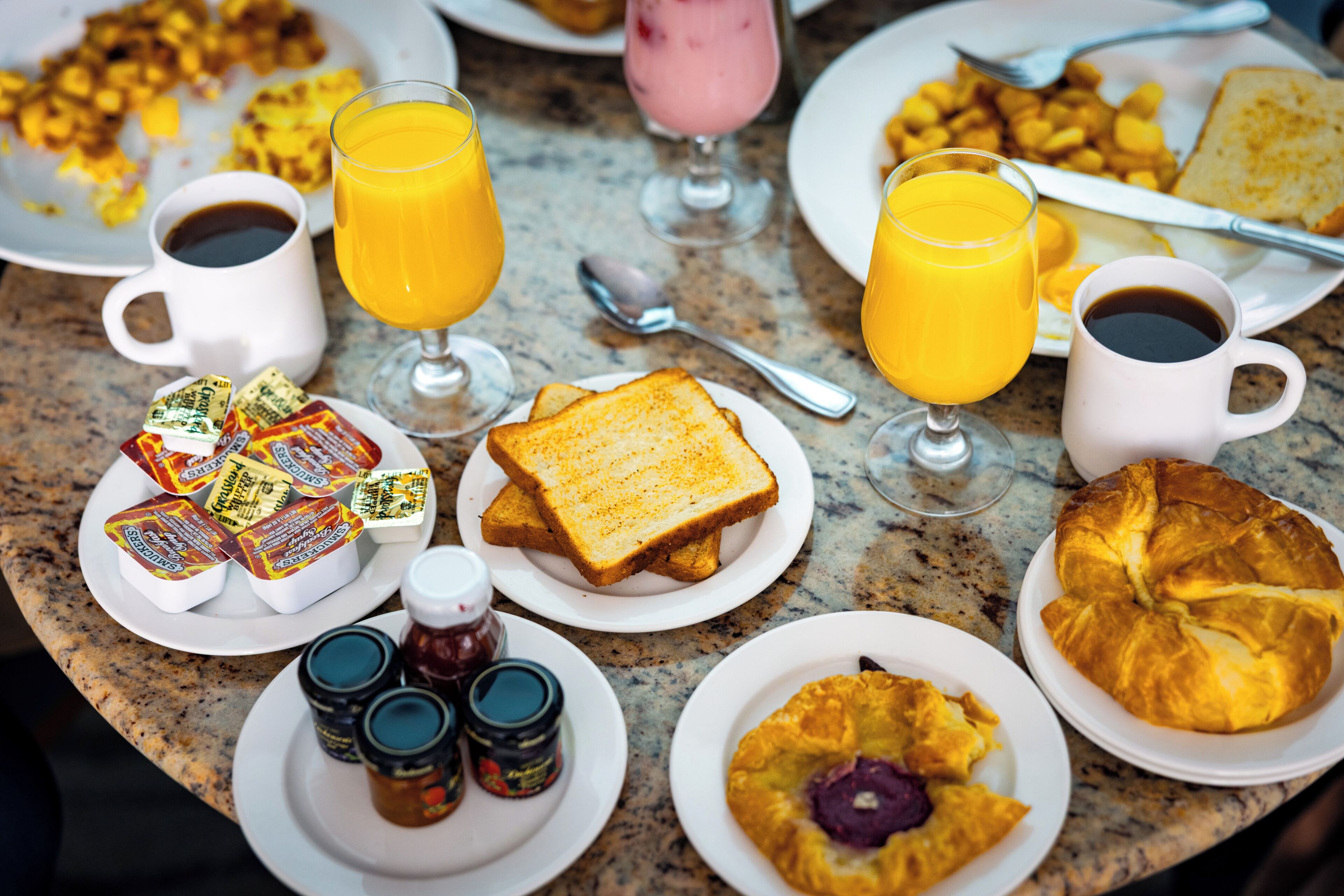 Ein Frühstückstisch mit Toast, Marmelade, Butter und Kaffee.