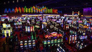 Een ruim casino met veel gokkasten en een rij kleurrijke, verlichte constructies op de achtergrond.