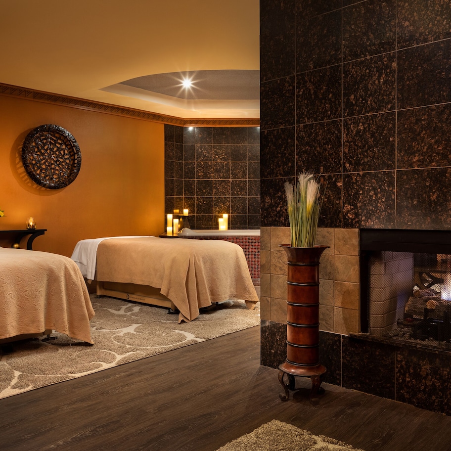 A spa room with two beds, a fireplace, and decorative wall art.