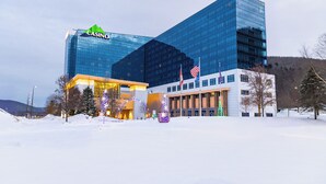 A modern casino building with a glass facade, American flags, and a snow-covered ground. - Seneca Allegany Resort & Casino (Salamanca)