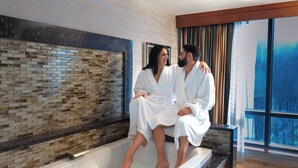 A couple in a modern bathroom with a mosaic wall, a bathtub, and a large window. - Seneca Allegany Resort & Casino (Salamanca)