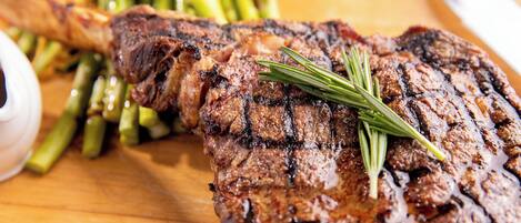 Bife com enfeite de alecrim sobre tábua de madeira.