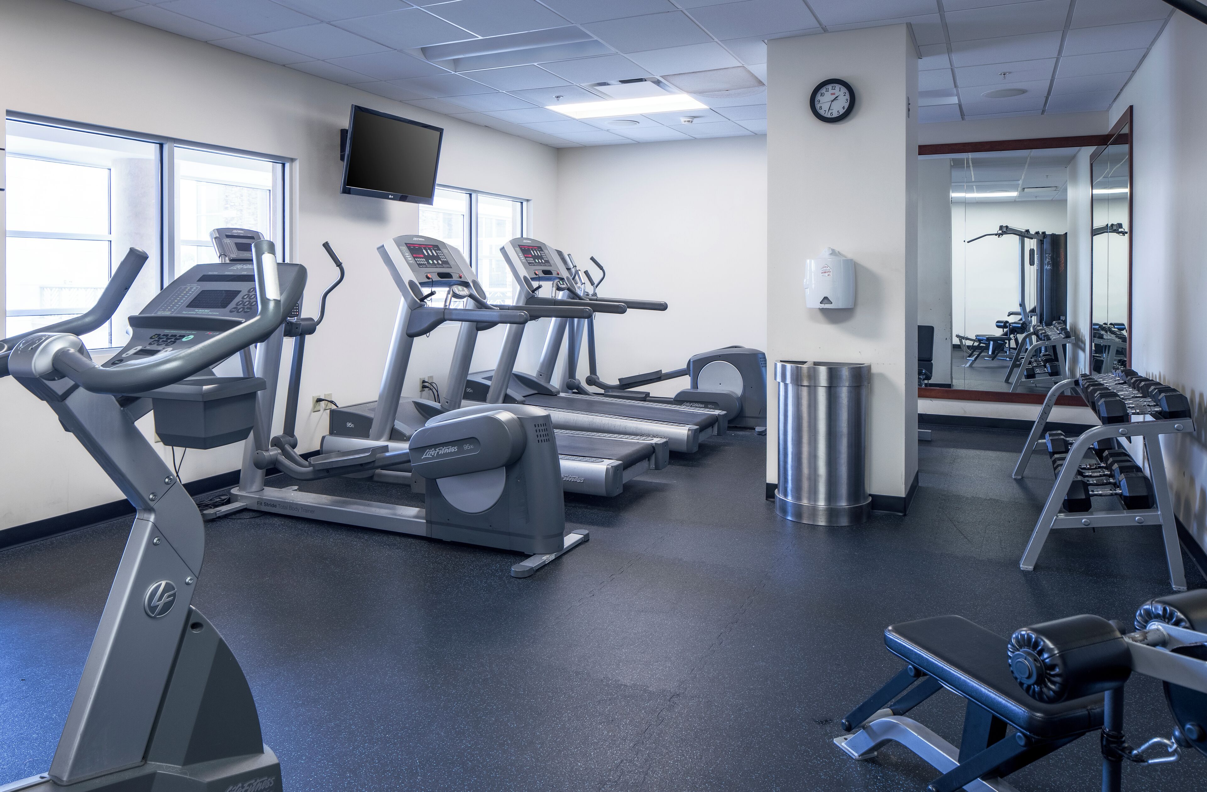 Une salle de sport équipée de tapis de course, de vélos elliptiques et de bancs de musculation.