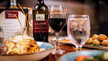 Una mesa de comedor con un menú, una botella de vino, una copa de vino y diversos platos.