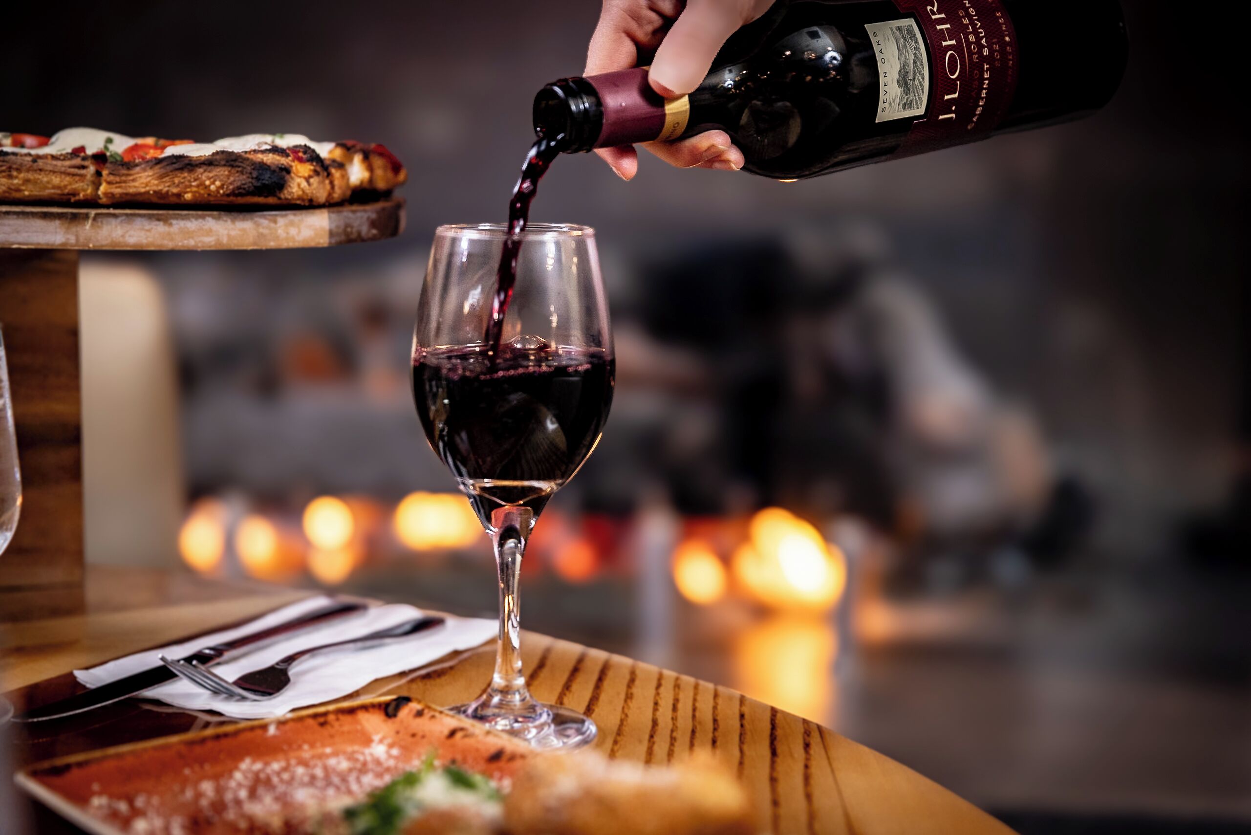 A bottle of wine being poured into a glass.