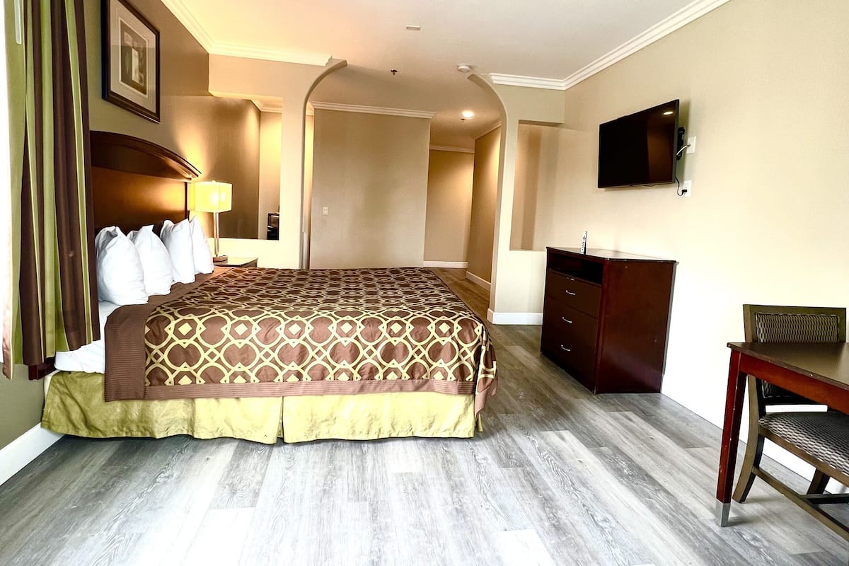 A hotel room with a large bed, a desk, a television, and a wardrobe.