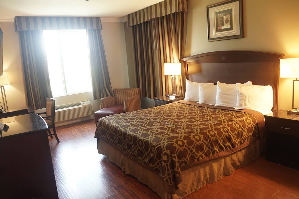 A hotel room with a large bed, a desk, a chair, a lamp, and a picture on the wall.