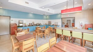 A modern restaurant with a blue and white color scheme, wooden furniture, and a central island with a red light fixture. - Country Inn & Suites by Radisson, Tallahassee-University Area, FL (Tallahassee)