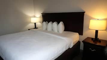 Een hotelkamer met een net opgemaakt bed, twee nachtkastjes met lampen, en een donker hoofdeinde.