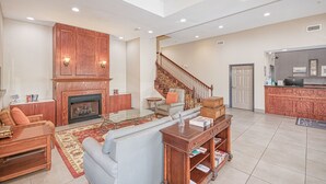 A spacious living room with a fireplace, a staircase, and a kitchen area. - Country Inn & Suites by Radisson, Tallahassee-University Area, FL (Tallahassee)