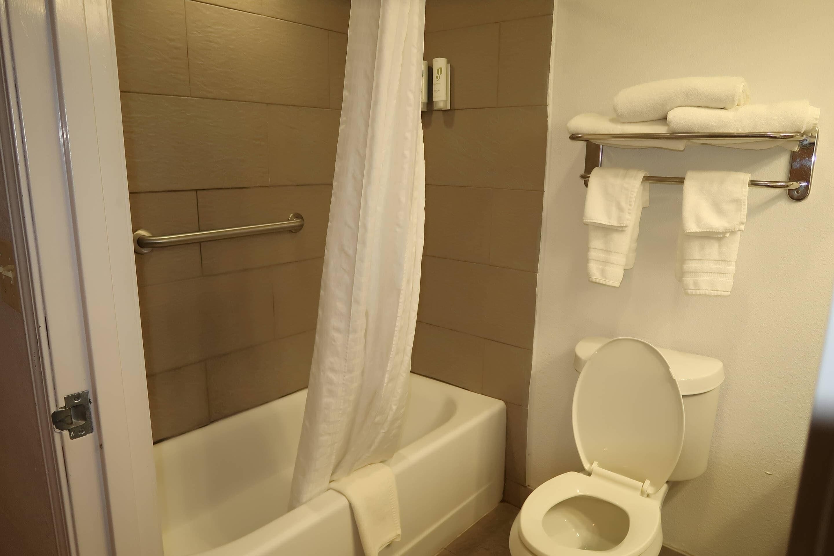 Um banheiro com banheira, vaso sanitário e porta-toalhas com toalhas.