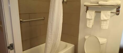 A bathroom with a bathtub, toilet, and a towel rack with towels.