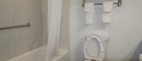 A bathroom with a bathtub, toilet, and towel rack.