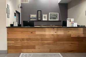 Ein Empfangsschalter mit Holzvertäfelung, gerahmte Bilder an der Wand und ein Dell-Computer auf der Theke.