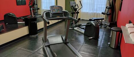 A gym with a treadmill, exercise bike, and various other fitness equipment.