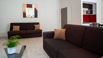A modern living room with two dark brown sofas, a glass coffee table with a plant, and a red and white abstract painting on the wall.